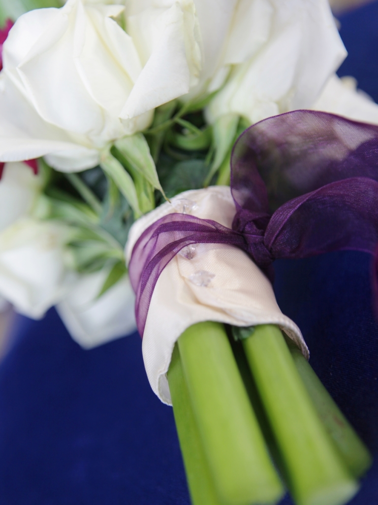 a close up of a bridal bouquet with white roses and purple accents